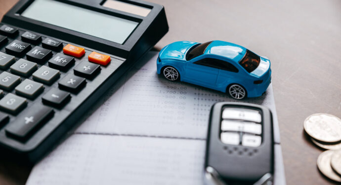 A toy car and car keys next to a calculator